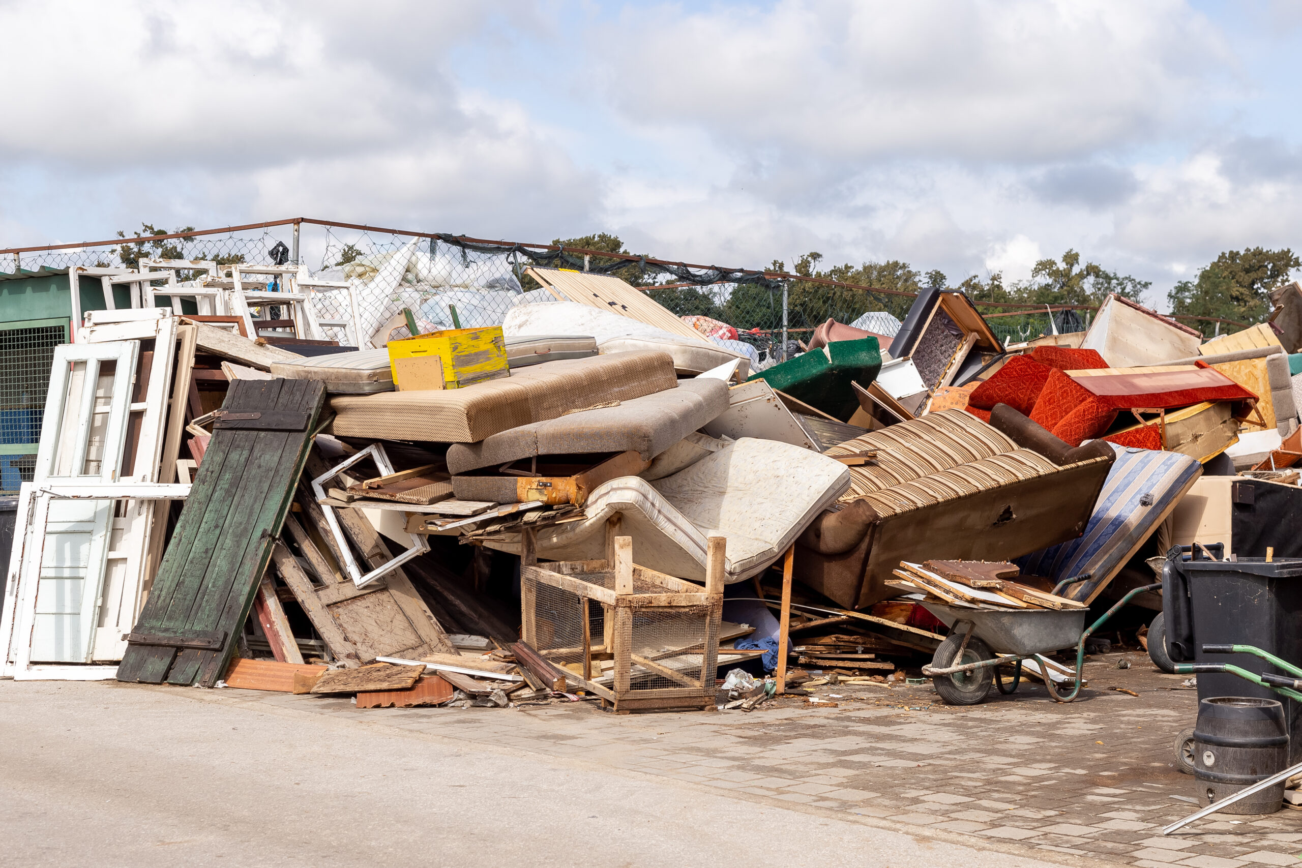 Pile of discarded furniture, including sofas, chairs, and wooden frames, at a recycling center, illustrating the need for professional junk removal services.